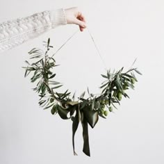 a woman is holding an olive wreath on a string