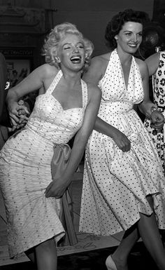 two women in dresses laughing and dancing together