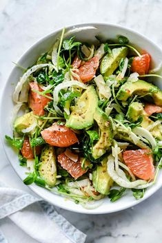 a white bowl filled with salad topped with avocado, tomatoes and lettuce