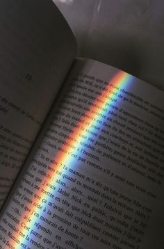 an open book with a rainbow in the middle and light coming from it's pages