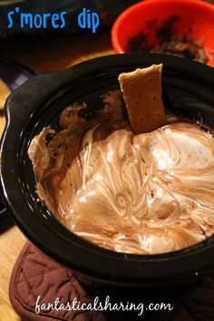 a bowl filled with peanut butter and crackers on top of a wooden table next to other dishes