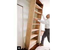 a man standing next to a tall book shelf with shelves on it's sides