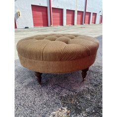 a brown ottoman sitting on top of a parking lot next to a red garage door