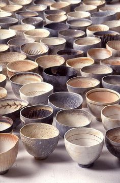 many bowls are lined up in rows on the floor and one is full of them