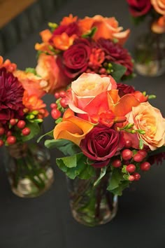 several vases filled with flowers on top of a black tablecloth covered table in front of a mirror