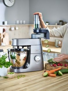 a woman is preparing food in her kitchen with a blender and cucumbers