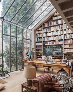 a living room filled with lots of furniture and bookshelves covered in glass walls