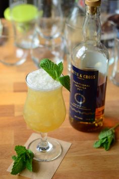 a bottle of alcohol sitting next to a glass filled with ice and mint