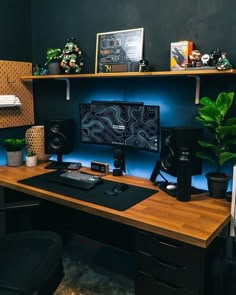 a desk with a computer and speakers on it in front of a shelf filled with plants