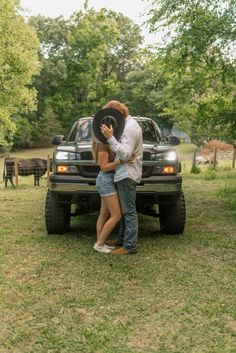 a man and woman standing in front of a truck with their arms around each other