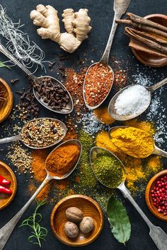 spoons filled with different types of spices and seasonings on top of a table