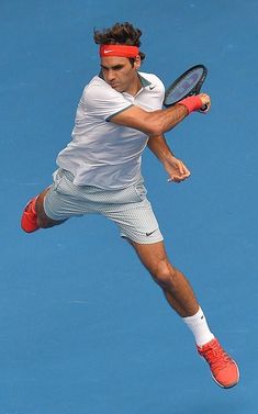 a male tennis player is in mid air after hitting the ball with his racket