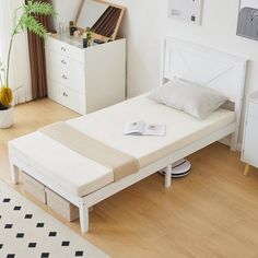 a white bed sitting on top of a wooden floor next to a dresser and mirror