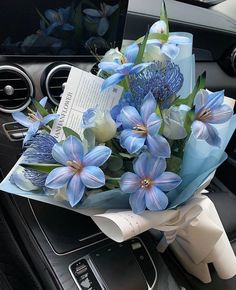 a bouquet of blue flowers sitting on the dashboard of a car