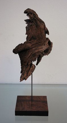 a piece of wood that is on top of a wooden stand in front of a white wall