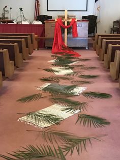 a church with palm leaves on the floor and red cloth draped over it's alter