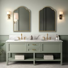 two mirrors are above the double sink vanity in this green bathroom with marble counter tops