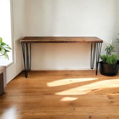 a wooden table sitting in the middle of a living room next to a couch and potted plant