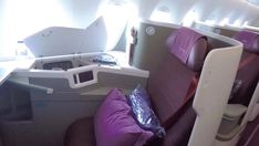 the inside of an airplane with lots of seats and purple pillows on each one side