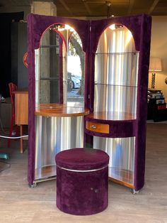 a purple cabinet with two mirrors and a stool