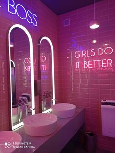 two sinks and mirrors in a bathroom with neon lights on the wall above them that read, girls do it better