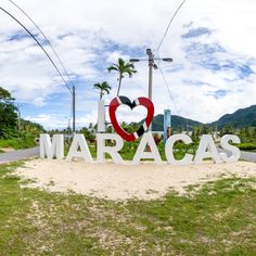 a sign that says i love maracas in front of some palm trees and mountains