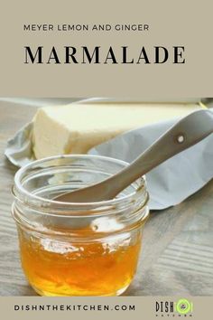 a jar filled with honey sitting on top of a wooden table next to a knife