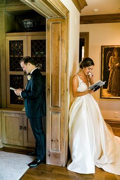 a bride and groom standing in front of a bookcase with wine glasses on it