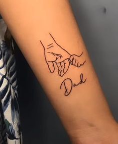 two hands holding each other with the word dad tattooed on their arm and behind them