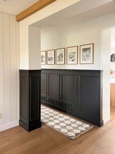 an empty living room with black cabinets and checkered rug on the hardwood flooring