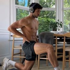 a man with no shirt and headphones is doing exercises on a yoga mat in the living room