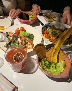 a table topped with plates and bowls filled with different types of food next to drinks