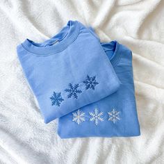 two blue snowflakes are laying on a white blanket and next to each other