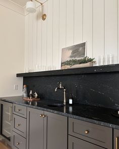 a kitchen with black counter tops and gold pulls on the cabinet doors is pictured in this image