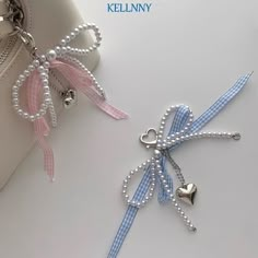 two key chains with bows and hearts attached to them on top of a white surface