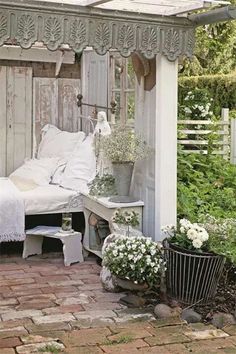 a bed sitting under a wooden structure next to a white bench and potted plants