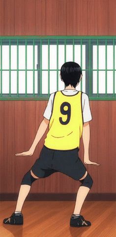 a boy in a yellow shirt and black shorts is standing on one leg with his hands behind his back