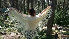 a woman is standing in the woods wearing a white crocheted shawl