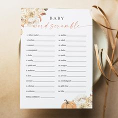 a baby word scramble on a plate next to some brown ribbon and flowers with gold foil