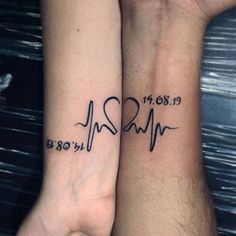 two people with matching tattoos on their arms holding each other's hands and one has a heartbeat