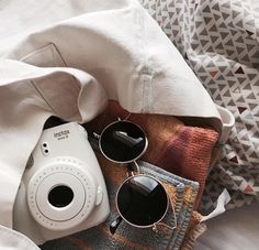 a white camera and some sunglasses on a bed