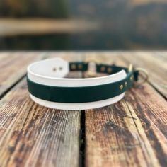 a green and white leather bracelet sitting on top of a wooden table