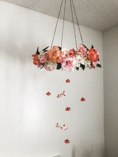 a white wall with flowers hanging from it's ceiling and butterflies flying around the room