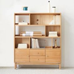 a book shelf with books and other items on it in front of a white wall