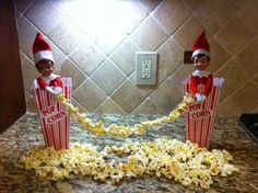 two elfs sitting on top of a counter with popcorn