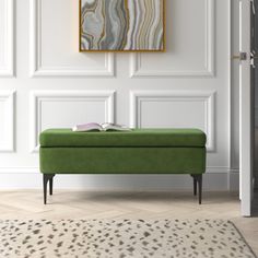 a green bench sitting in front of a white wall with a painting on the wall