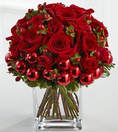 a vase filled with red roses and greenery