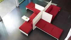 a red and white couch sitting on top of a black floor next to a table