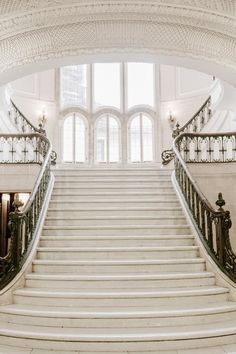 an ornate staircase with wrought iron railings leading up to the second floor in a large white building