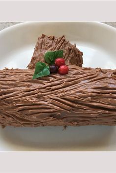 a piece of chocolate cake on a white plate with cherries and green leafy garnish